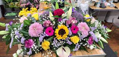 Brightest Memories Spray - A vibrant and uplifting casket spray designed in radiant shades of pink, yellow, lilac, and ivory. Filled with striking textures and graceful seasonal details, this arrangement offers a heartfelt tribute celebrating a life full of warmth, joy, and cherished memories.